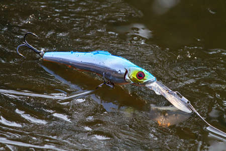 blue minnow wobbler lies on the rim ice in the riverの写真素材
