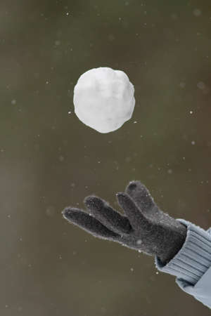 a woman's gloved hand toss a snowball made of fresh snowの写真素材