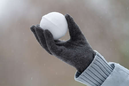 gloved hand holds a snowball made from fresh snowの写真素材