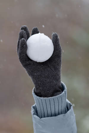 gloved hand holds a snowball made from fresh snow highの写真素材