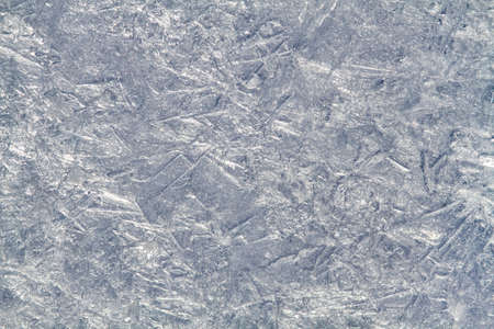 The patterned surface of the ice, covered with furrows, bumps and air bubbles. Abstract winter background for Christmas.の写真素材