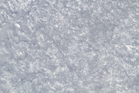 A light patterned surface of ice formed by small rounded pieces of ice and air bubbles. Through it...