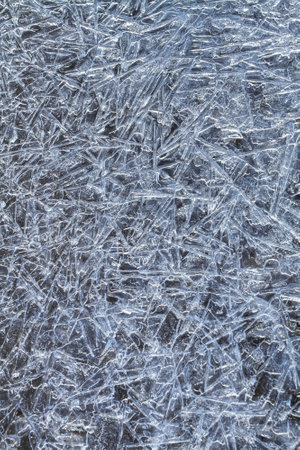 A patterned surface of ice, consisting of melted and then frozen ice needles on a dark background. Abstract winter background for Christmas.の写真素材