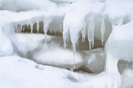 A large ice floe is covered with snow. During the thaw, icicles of bizarre shape grew in it.の写真素材