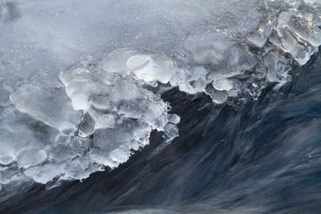 River water flows quickly along the edge of the shore ice. The edge of the ice is treated with water...