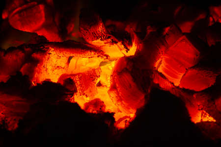 Hot coals glow orange in the dark of the stove.の写真素材