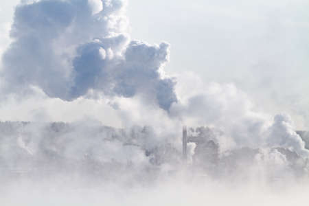 On a frosty day, smoke rises from factory chimneys above the factory. Fog is spreading in the foreground.の写真素材