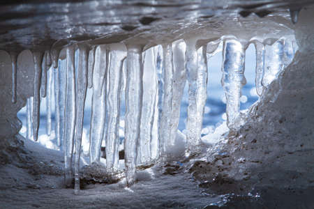 A row of icicles blocks the entrance to an ice cave on the seashore. A look from the inside.の写真素材