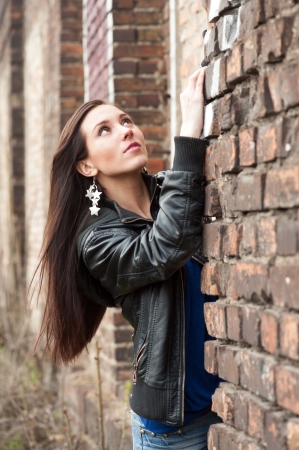Young pretty girl in black leather jacket near the brick wallの写真素材
