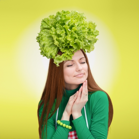 Portrait of pretty smiling woman with the salad on her headの写真素材