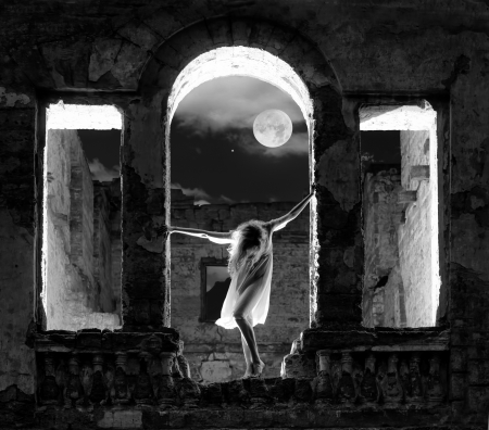 Mysterious female figure standing in the arc of the ruined building in full moon night, black and white shotの写真素材