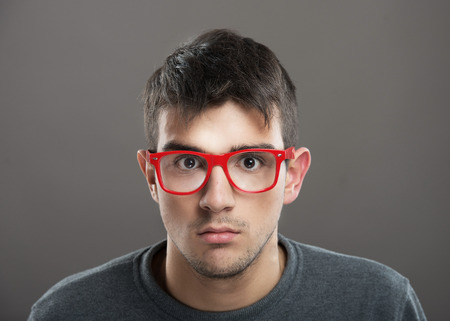 Teenage boy in red-framed eyeglasses looking at cameraの写真素材