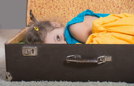 Dreaming little girl lying in an old suitcaseの写真素材