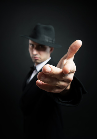 Man in the black trench coat and hat stretching his hand toward the cameraの写真素材