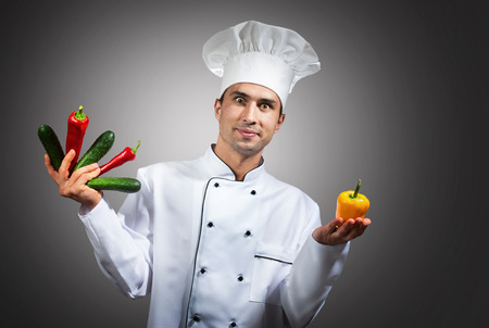 Humorous portrait of a chef with vegetables in his hands looking at cameraの写真素材