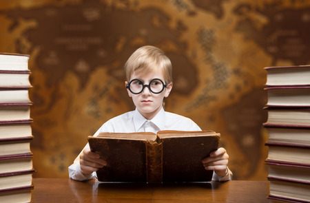 Retro style portrait of a reading boy against an old world mapの写真素材