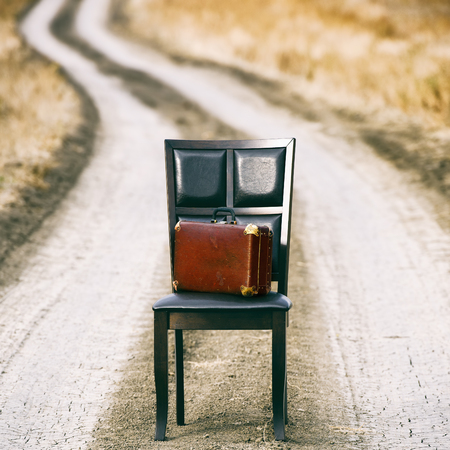 Wooden chair and old suitcase on the rural pathの写真素材