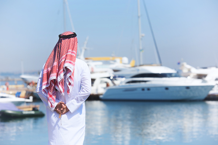 Arabian man looking at the yacht harbor, back viewの写真素材