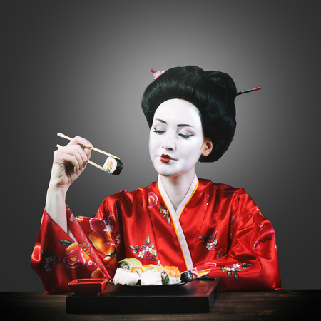Woman in geisha makeup eating sushiの写真素材
