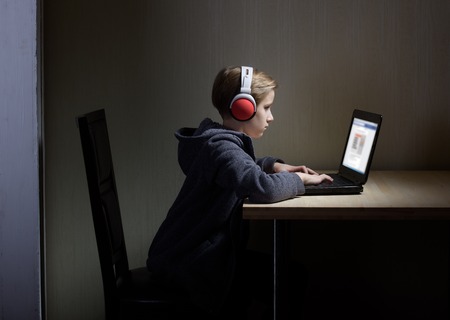 Tween son in headphones looks at a computer screenの写真素材