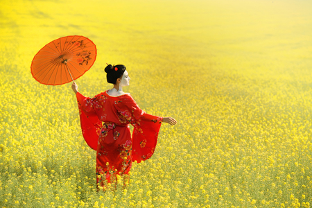 Woman in geisha makeup walking under an umbrella in the fieldsの写真素材
