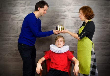 Parents put a crown on the head of their son. Permissive (indulgent) parentingの写真素材