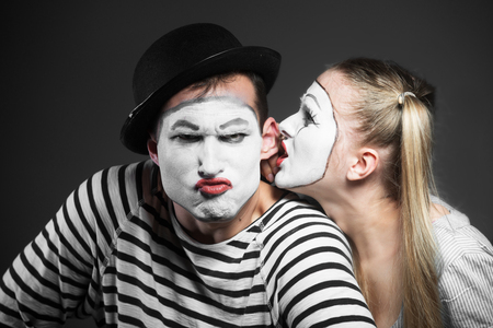 Female mime sharing secret with angry male mimeの写真素材