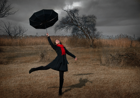 Woman with umbrella turning inside out by the windの写真素材