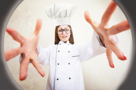Funny portrait of a female chef reaching for the saucepan, view from belowの写真素材