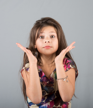 Portrait of an expressive preteen girl, studio shot, gray backgroundの写真素材