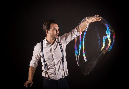 Artist hold big soap bubble in his hands. Bubble show studio concept.の写真素材