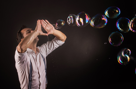 Artist blowing many soap bubbles from his hands. Bubble show studio concept.の写真素材