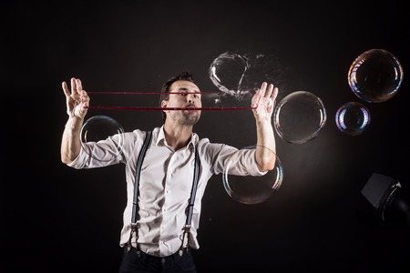 Artist blowing many soap bubbles from his hands. Bubble show studio concept.