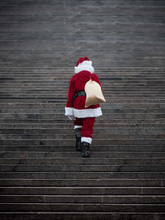 Santa claus climbing stairs. Present delivery concept .の写真素材