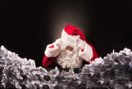 Santa clause with a great heap of crumpled papers. Cristmas crysis concept.の写真素材