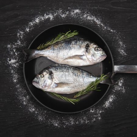 Fresh fixh dorado on a frying pan on a dark background. View from above.の写真素材