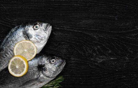 Fresh fish dorado. Dorado and ingredients for cooking on a black table.の写真素材