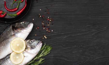 Fresh fish dorado. Dorado and ingredients for cooking on a black table.の写真素材