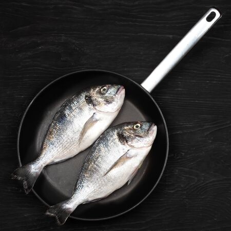 Fresh fixh dorado on a frying pan on a dark background. View from above.