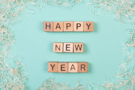 Happy new year phrase compiled with a wooden blocks on mint background with delicate curly decor.の写真素材