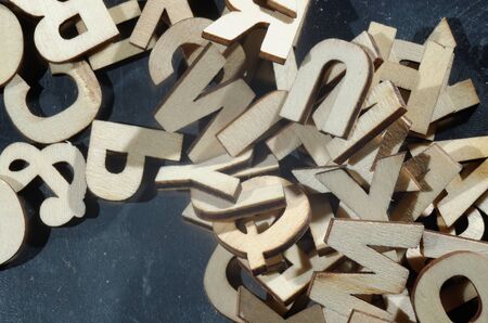 A jumbled pile of wooden letters on a metal surface