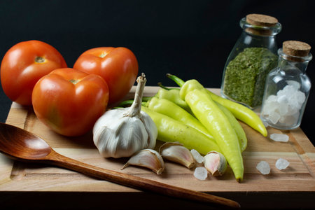 Fresh vegetables and spices on a wooden board on a black background.