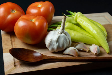 Tomatoes, garlic and pepper on a wooden board. Black background.の写真素材