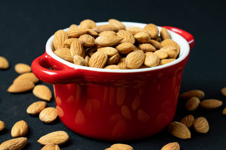 almonds in a red bowl on a dark background close-upの写真素材