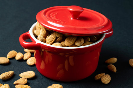 Almond in a red pot on a black background close-upの写真素材