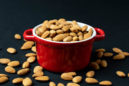 Almond in red bowl on black background. Healthy food concept.の写真素材