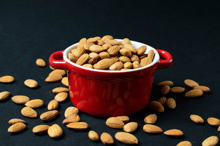 Almond in a red pot on a black background. Close up.の写真素材