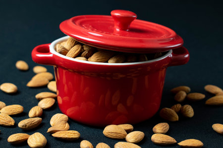 almonds in a red pot on a black background, closeupの写真素材