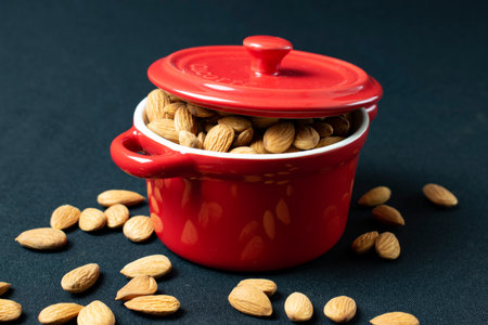 almond in red pot on black background. Healthy food concept.の写真素材