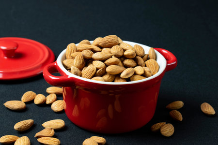 Almond in a red bowl on a black background, selective focusの写真素材